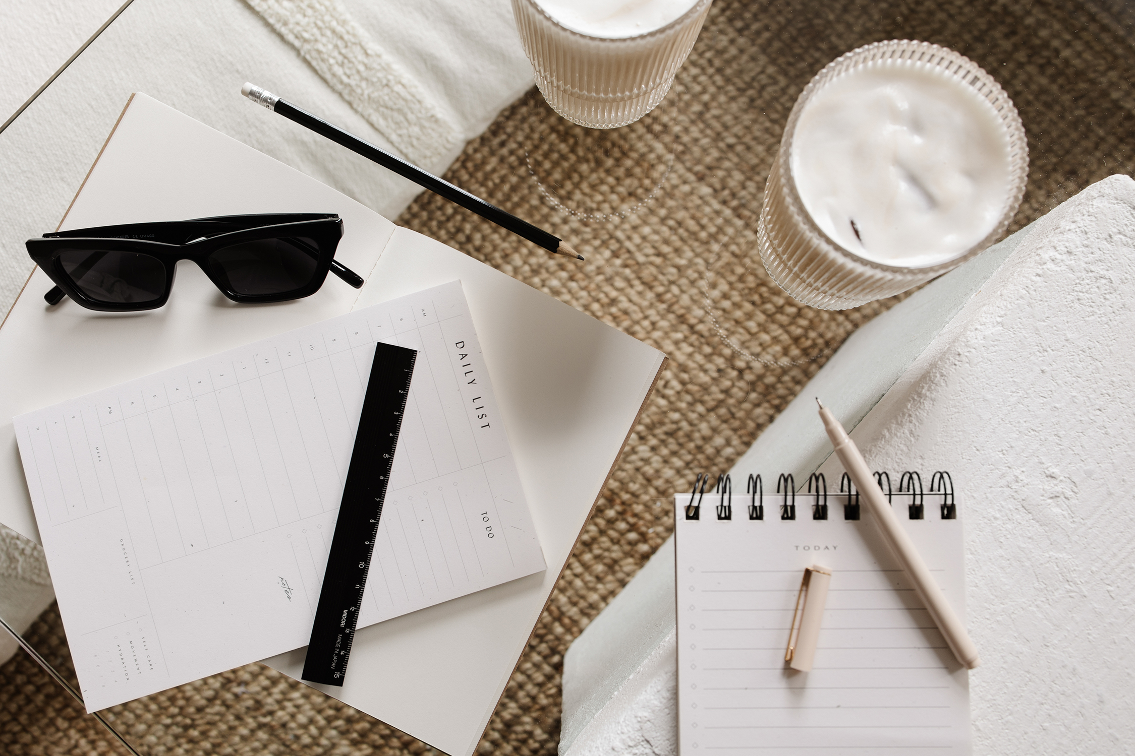 flat lay image of note pad, pen, drink, and sunglasses