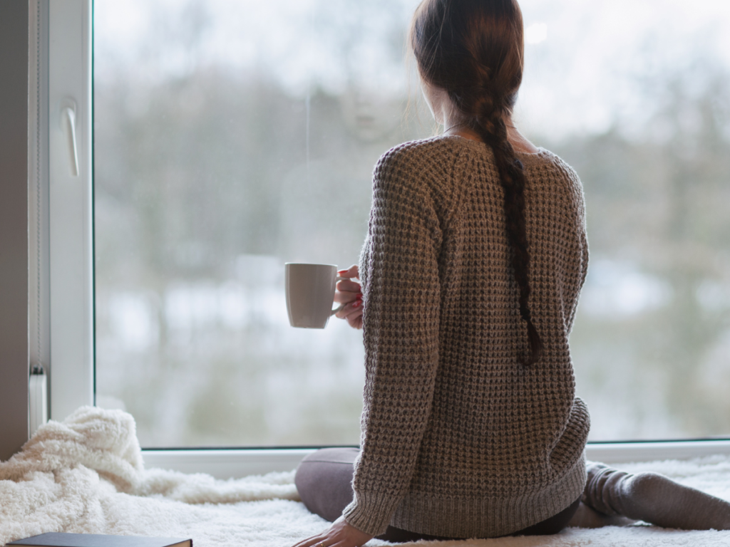 A sitting with a cup of tea looking out the window