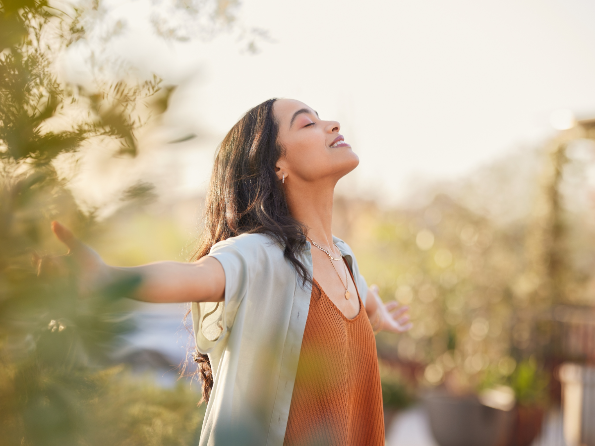 dark haired women standing with arms spread out wide and smile on her face