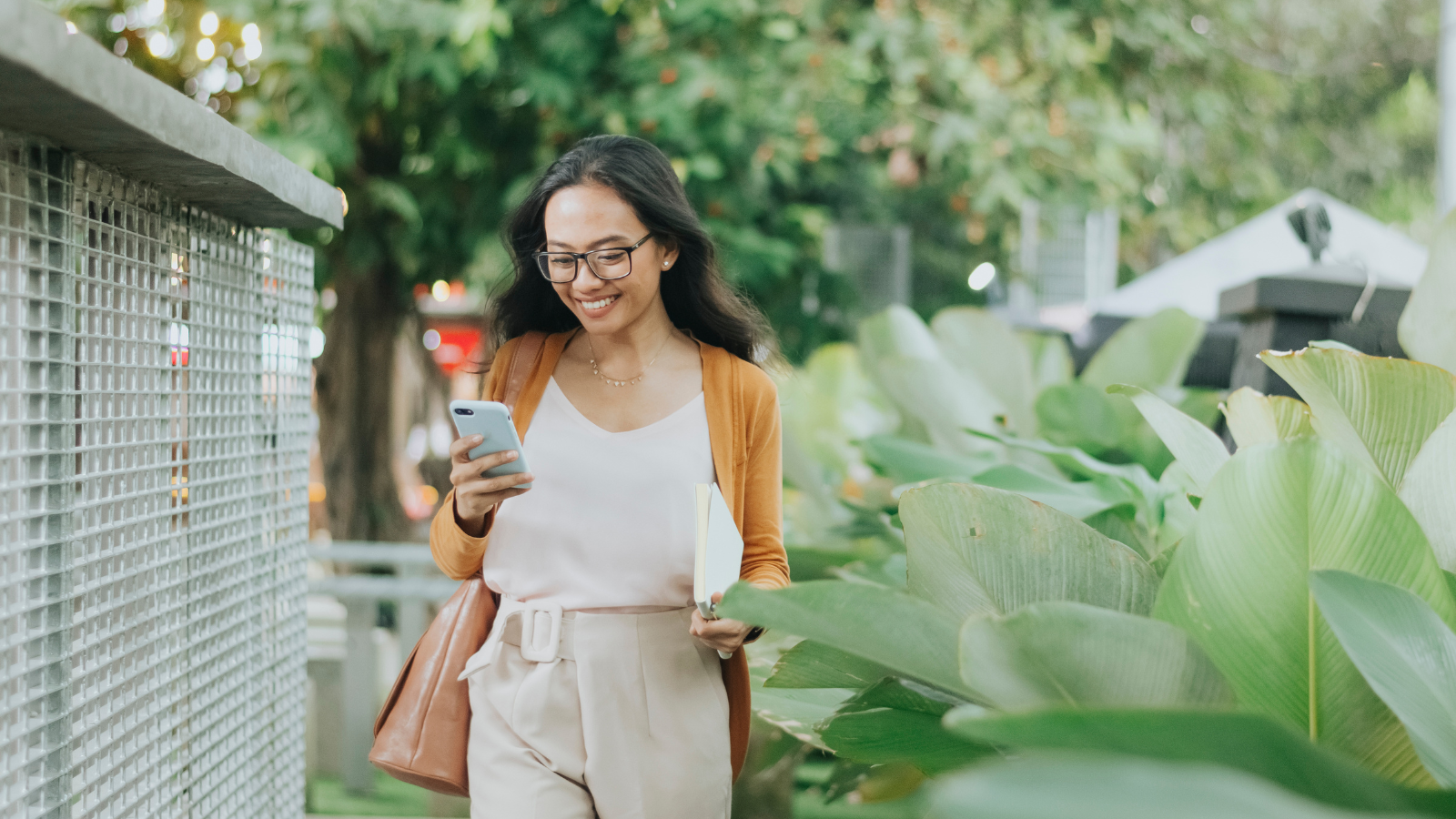 woman smiling looking at phone walking outside